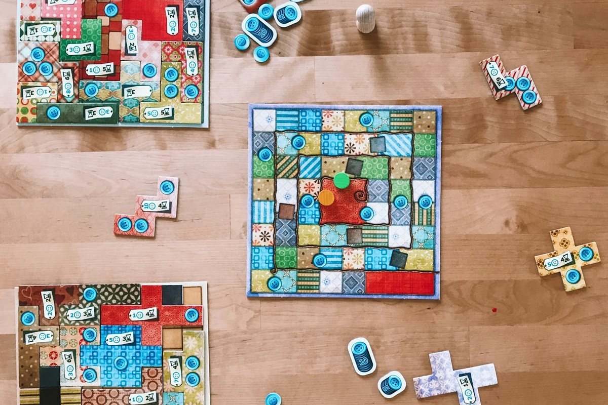 Colorful patchwork board game pieces arranged on a wooden table