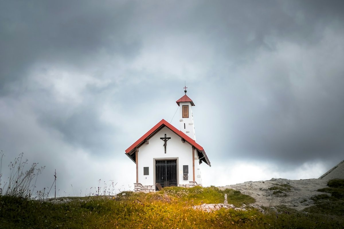 a small church on a hill under a cloudy sky